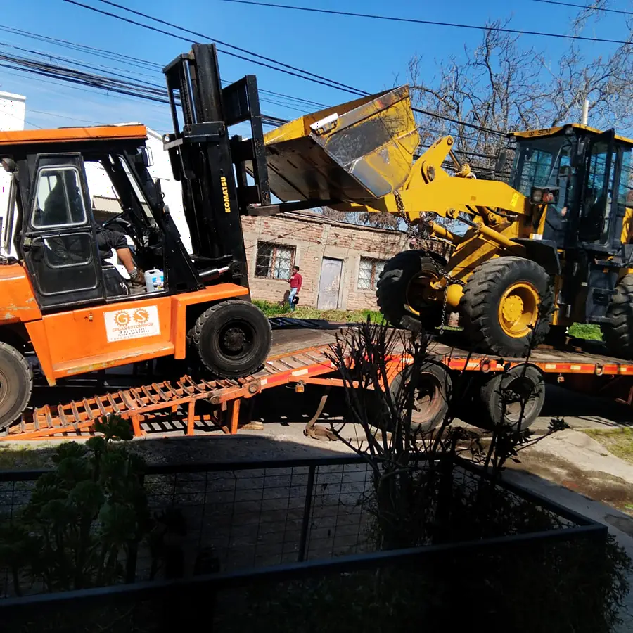 Grúa horquilla y cargador frontal montados sobre la cama baja para su traslado