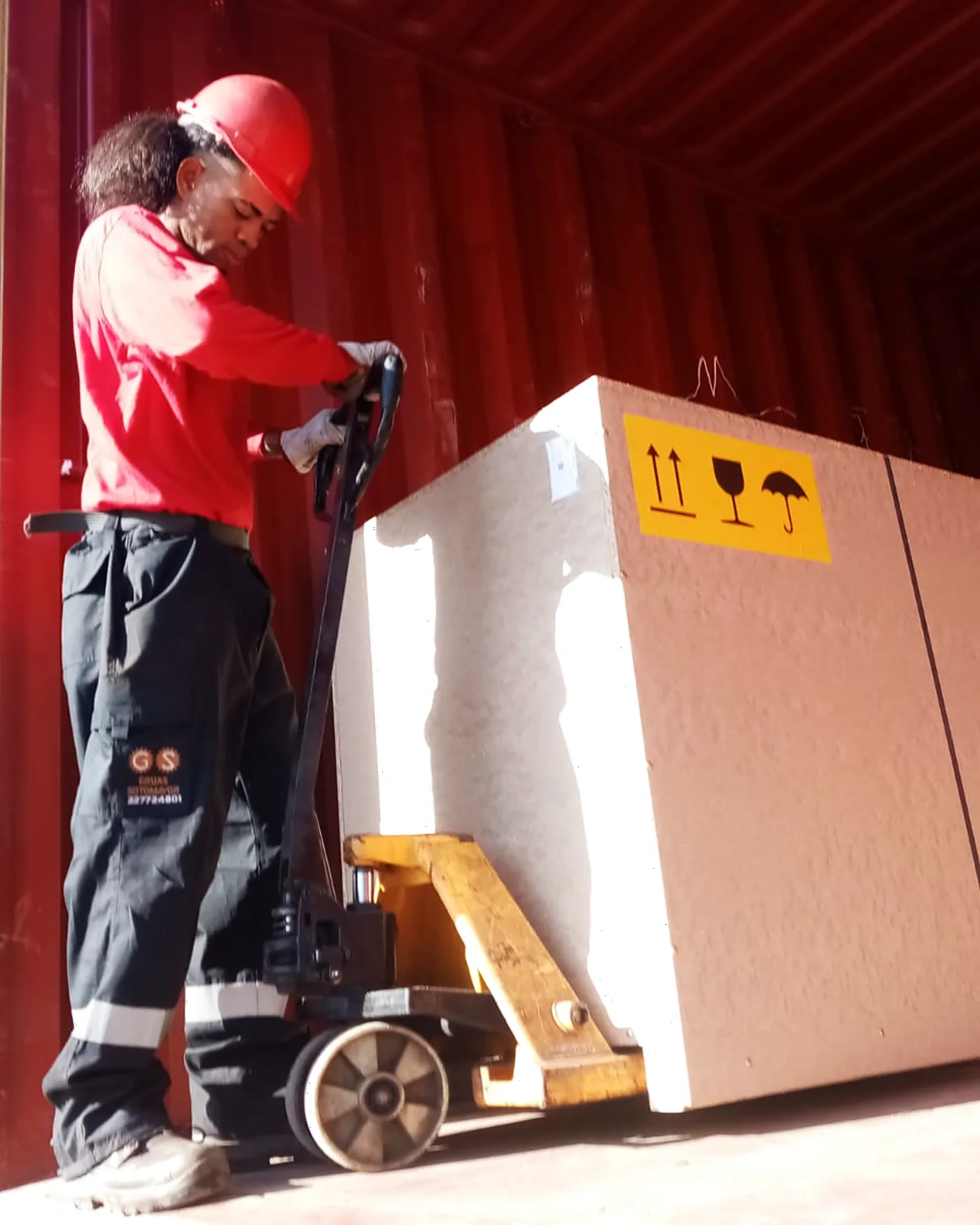 Rigger moviendo una plancha de mármol con transpaleta dentro del contenedor